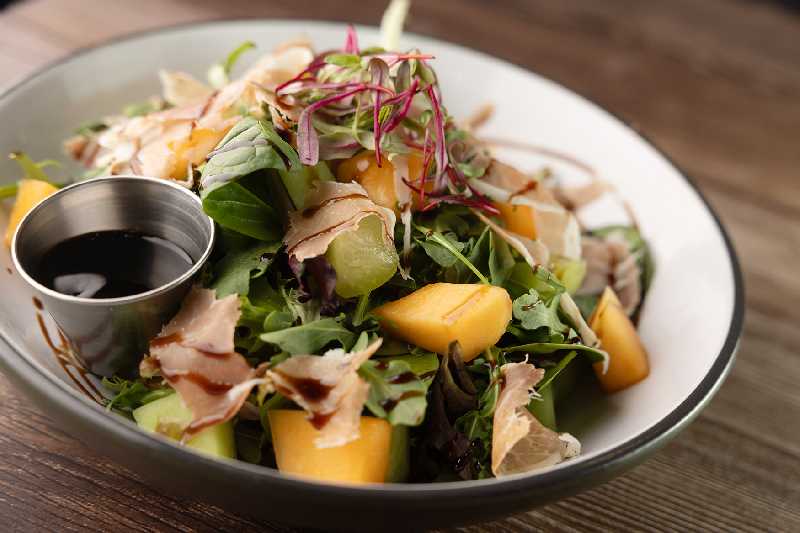 Melon and Prosciutto Salad with Balsamic Drizzle - A refreshing salad featuring juicy melon slices, savory prosciutto, and a drizzle of balsamic glaze, available at Brekki Brekki. Perfect for those searching for brunch near me or food near me.